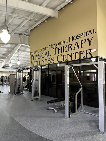 image of the physical therapy and wellness center sign on the wall above gym equipment