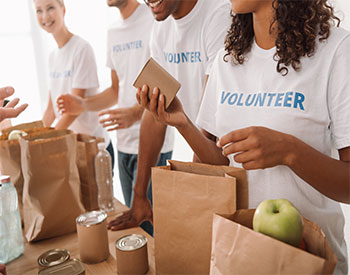 cropped shot of young volunteers group packing food and drinks for charity