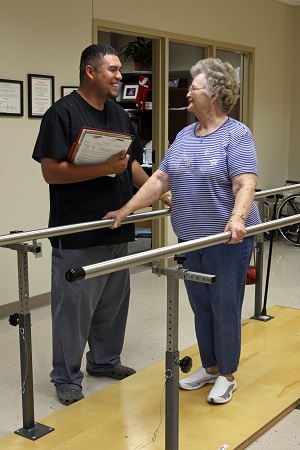 This is a picture of a physical therapist helping a elderly person walk.