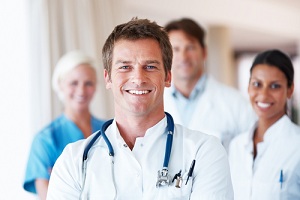 This is a picture of a doctor and three others behind him smiling as well.